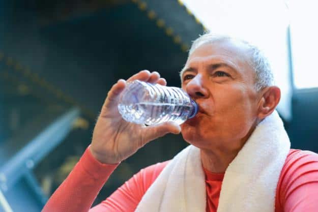 Elderly Man in Red Shirt Drinking Water from a Plastic Bottle | Alzheimer's and Dehydration