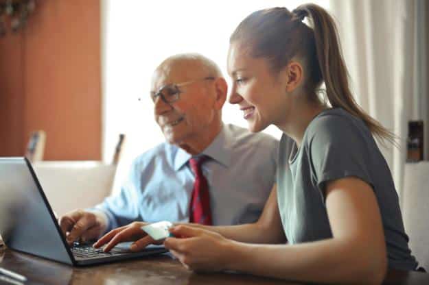 Young woman helping senior man with payment on Internet using laptop px | Gadgets for Seniors