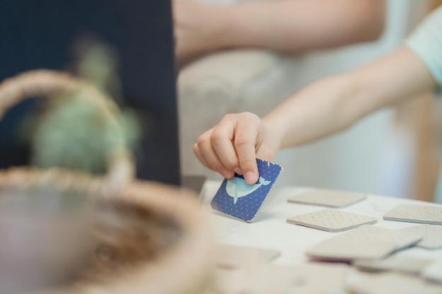 A Kid's Hand Holding a Blue Card | Memory Games for Seniors px