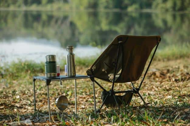 Camping chair near table on river shore | camping for seniors px