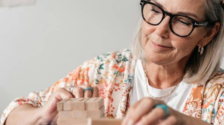 Elderly Woman in Floral Shirt Stacking Wooden Blocks | Memory Games for Seniors px featured image