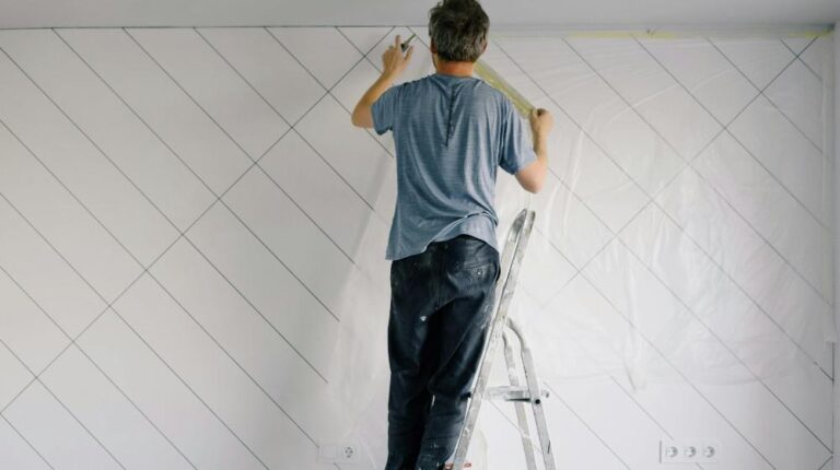 Faceless house painter undercoating wall in bright room | home maintenance for seniors px featured image