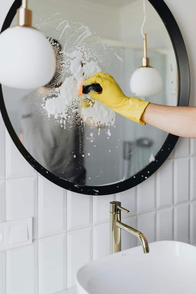 Faceless person cleaning mirror in bathroom | home maintenance for seniors px