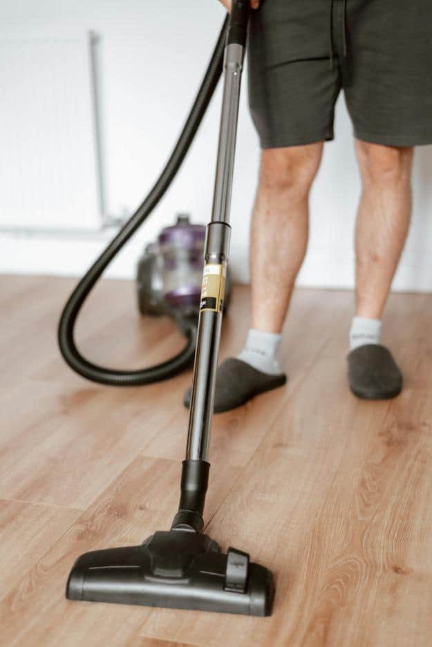 Man vacuuming floor with cleaner in home | home maintenance for seniors px