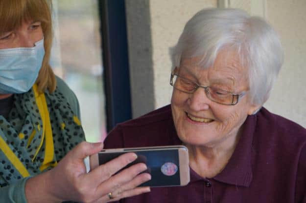 woman in brown button up shirt holding white smartphone | questions to ask assisted living us