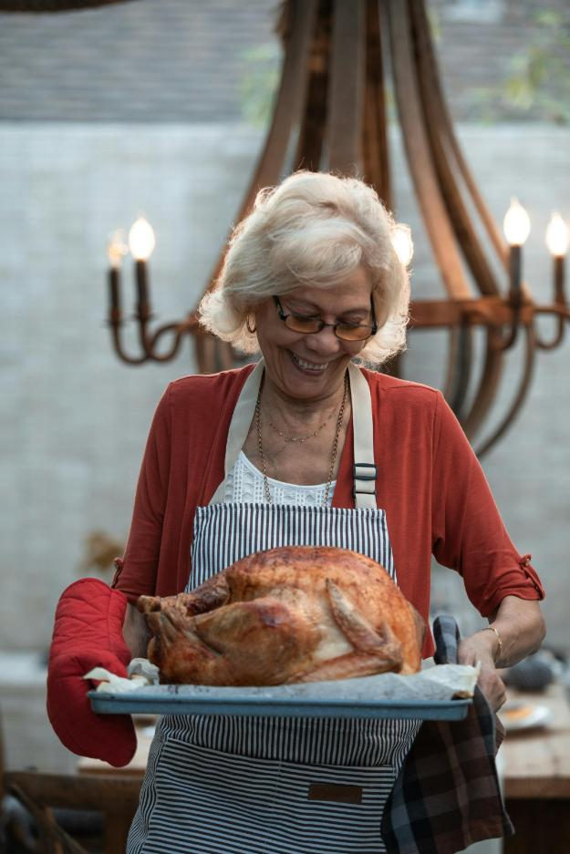Woman in Red Cardigan Holding Roasted Chicken | Thanksgiving Celebration Ideas for Seniors px