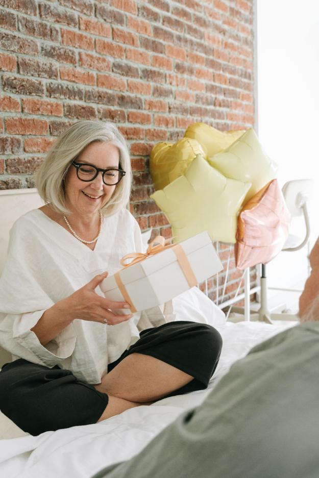 Woman in White Long Sleeve Shirt Sitting on the Bed Holding a Gift | Black Friday Gift Ideas for Seniors px